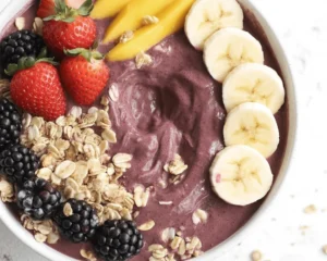 Homemade acai bowl topped with fresh fruits and granola in a vibrant bowl.