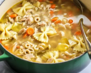 A bowl of hearty turkey soup garnished with fresh herbs and vegetables.