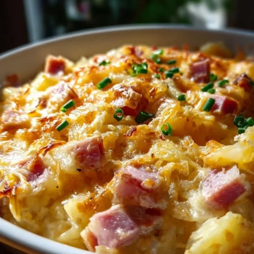 Cheesy ham and potato casserole served in a baking dish with fresh herbs on top