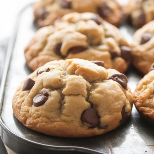 Freshly baked chocolate chip muffins topped with extra chocolate chips and sugar.