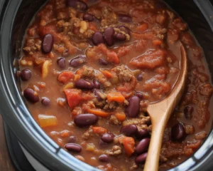 Delicious crockpot chili recipe with ground beef, beans, and spices simmering in a slow cooker.