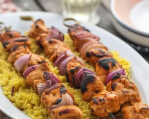 Grilled chicken kebabs served with fresh vegetables and herbs.
