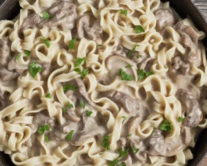 Creamy ground beef stroganoff served in a bowl with pasta and garnish.