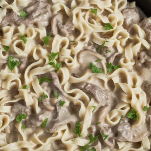 Creamy ground beef stroganoff served in a bowl with pasta and garnish.