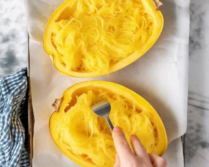 Baked spaghetti squash with cheese and herbs served in a dish.