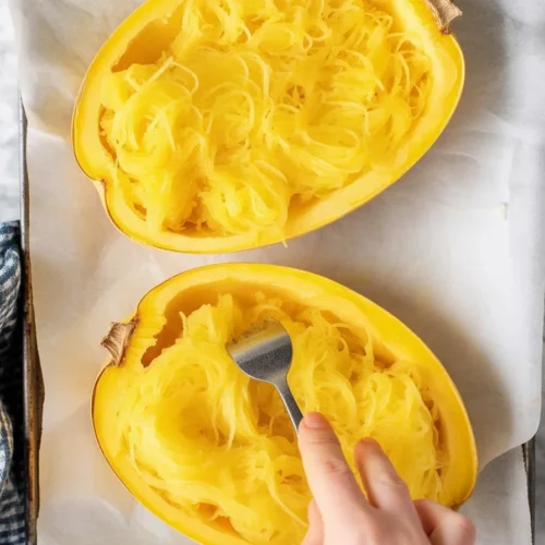 Baked spaghetti squash with cheese and herbs served in a dish.