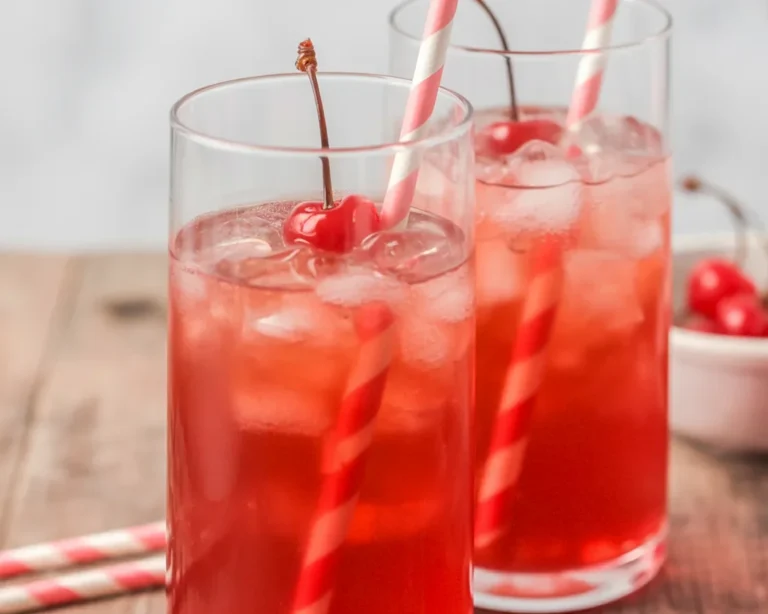 Refreshing Shirley Temple drink with grenadine, ginger ale, and maraschino cherries.