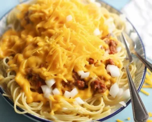 Delicious bowl of Cincinnati chili served over spaghetti with toppings