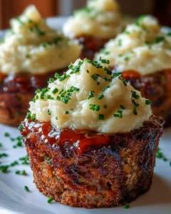 Meatloaf cupcakes topped with whipped potato frosting on a white plate.