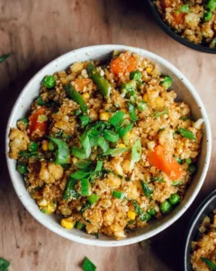 Bowl of delicious cauliflower fried rice with vegetables and herbs.