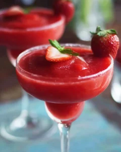 Delicious frozen strawberry daiquiris served in a glass with strawberries