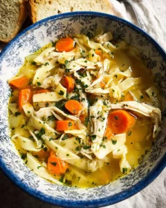 A bowl of homemade chicken noodle soup garnished with fresh herbs