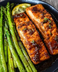 Honey garlic salmon fillet served with asparagus on a white plate