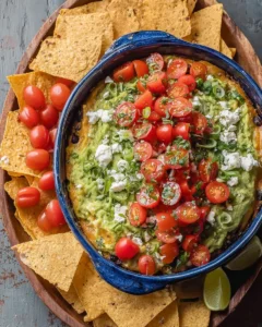 Layered bean dip topped with guacamole in a serving dish