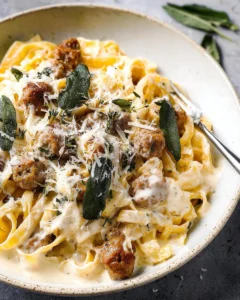 Creamy sausage alfredo pasta garnished with fried sage leaves