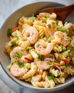 Shrimp pasta salad served in a bowl with fresh vegetables and dressing