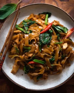 Delicious plate of Thai Drunken Noodles (Pad Kee Mao) garnished with fresh basil.