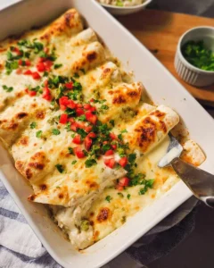 Delicious white chicken enchiladas topped with cheese and served on a plate.