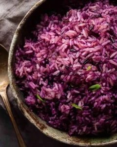 Bowl of purple rice with vibrant red cabbage garnish, healthy and colorful dish.