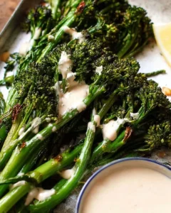 Plate of roasted broccolini drizzled with tahini sauce