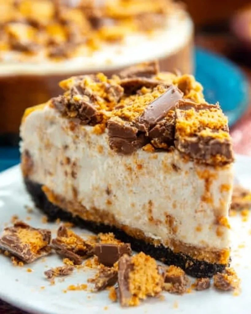 Delicious Butterfinger Cheesecake topped with chocolate and crushed Butterfinger bars