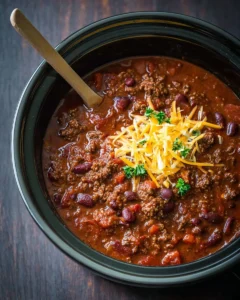 Bowl of classic slow cooker chili topped with cheddar cheese and cilantro