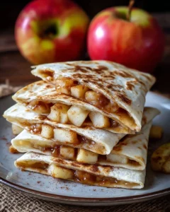 Apple cinnamon breakfast quesadillas served on a plate with syrup drizzle.