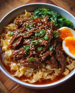Bowl of Korean beef noodles topped with green onions and sesame seeds.