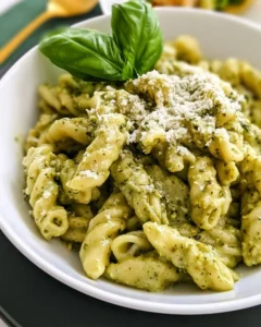 Plate of creamy pesto pasta garnished with basil and pine nuts