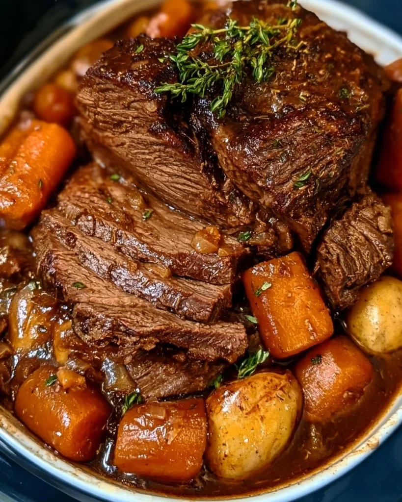 Slow cooker shredded roast beef piled on a roll with au jus