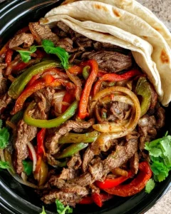 Delicious slow cooker steak fajitas served with peppers and onions